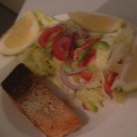 Seared salmon served with salad and lemon wedges
