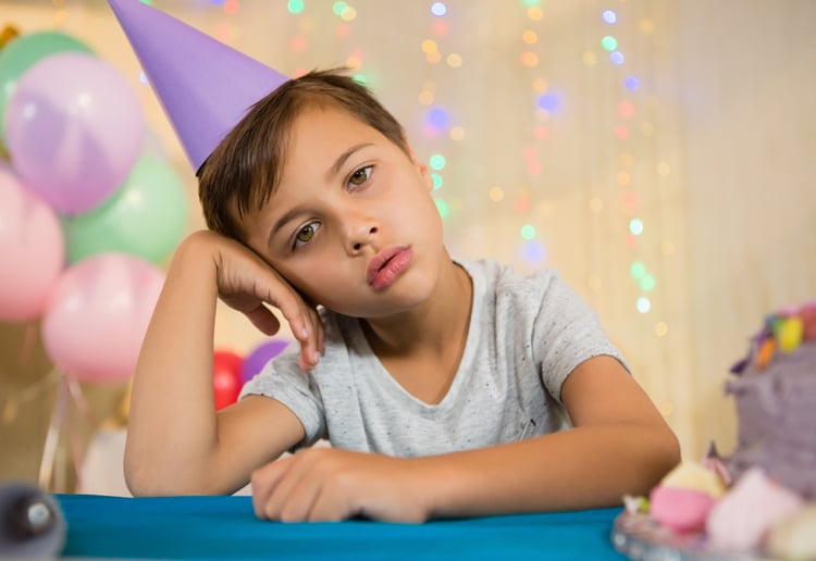 Boy sitting near a birthday cake at home