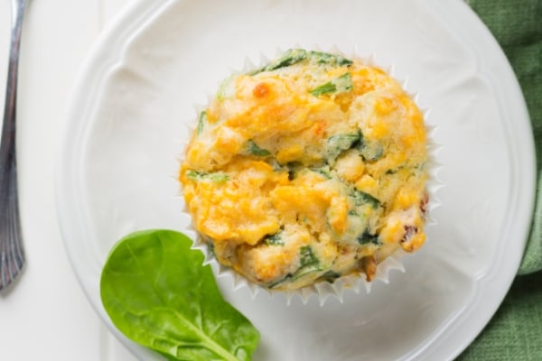 Golden Fritatta Muffin filled with Tassal Salmon served on a white plate with baby spinach garnish