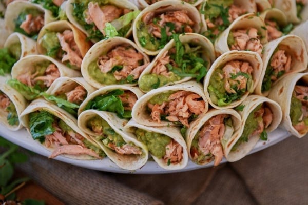 Plate of burrito wraps filled with fresh salmon, avocado and lettuce piled high