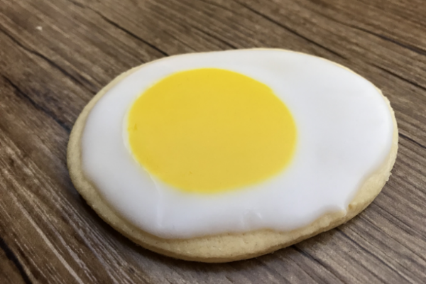 Oval shaped biscuits topped with white icing and then a yellow centre to look like a sunny side up egg