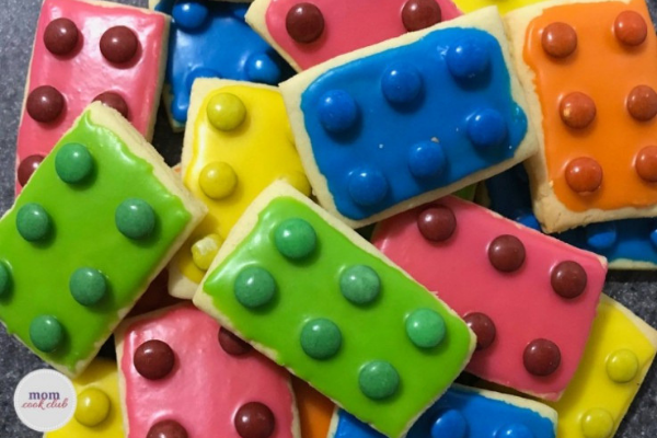 Butter cookies cut into small rectangles decorated with brightly coloured icing and matching colour mini m&ms to create a lego brick