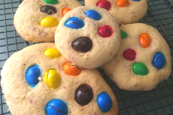 Round vanilla biscuits topped with peanut m&ms in a variety of colours