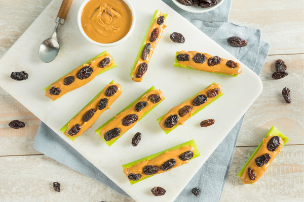 sticks of celery filled with peanut butter with sultanas placed on top to resemble ants on a log