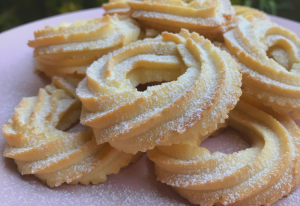 A batch of freshly made Italian Shortbread Cookies served on a pink plate dusted with icing sugar