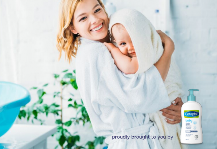 Picture of mother in white bathrobe with adorable baby in white bath towel with blue baby bath in the background