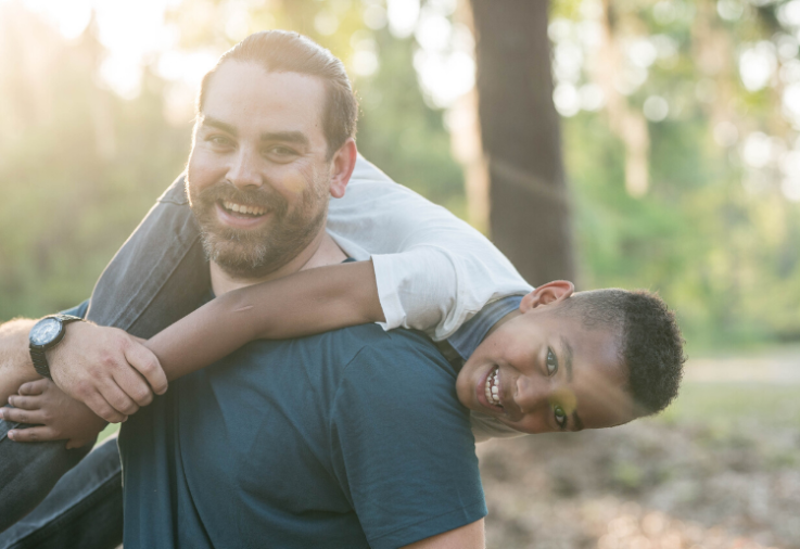 A strong boy names his father as champion of romping as they play together in the forest