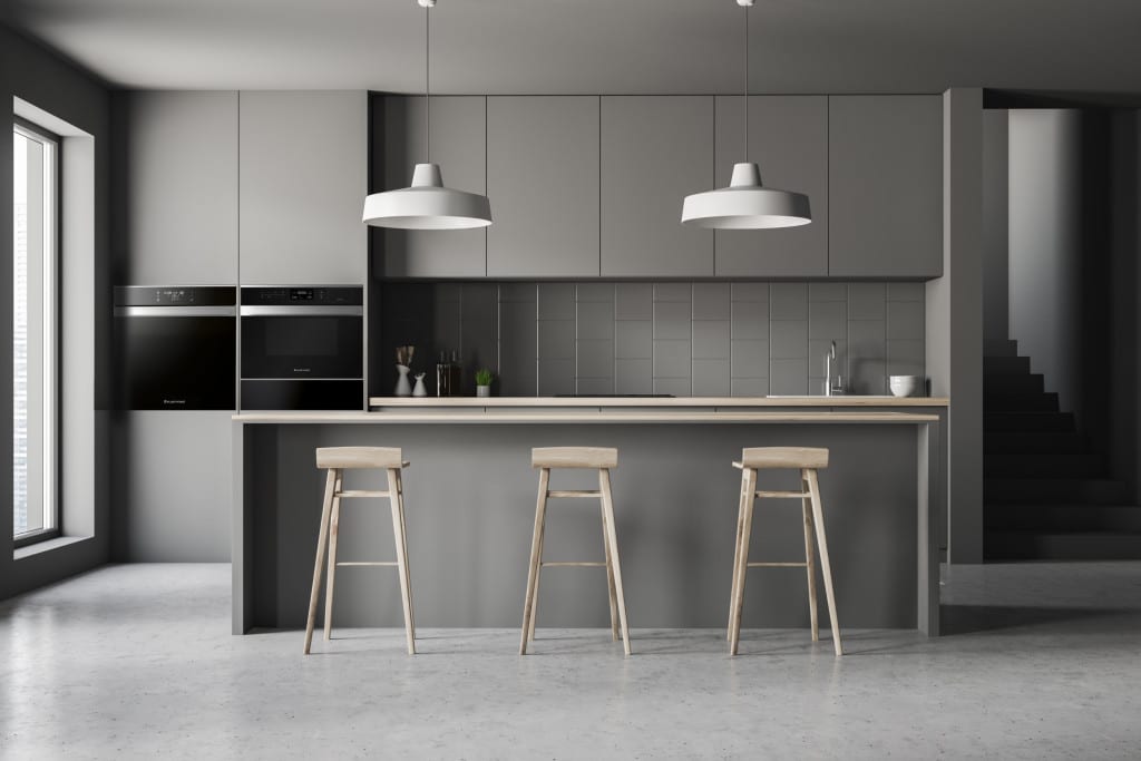 Interior of modern kitchen with gray walls, concrete floor, gray countertops and cupboards and gray and wooden bar with stools. 3d rendering