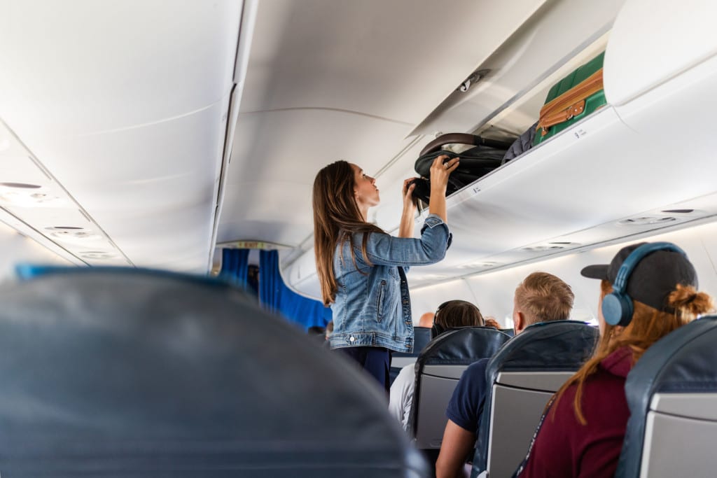 Woman putting a stroller into an overhead locker on a plane