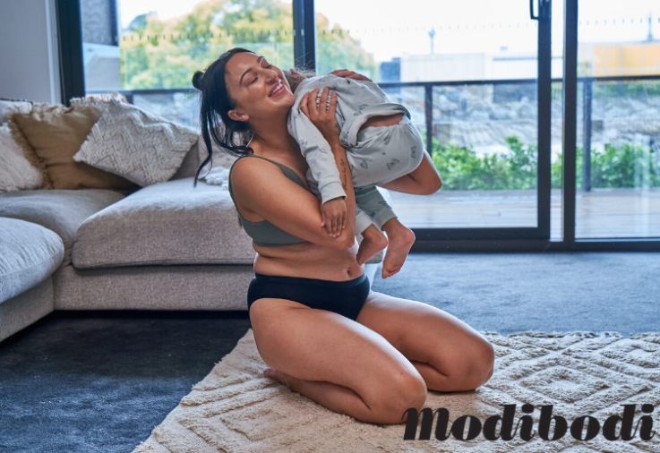 A woman playing with her baby wearing ModiBodi underwear