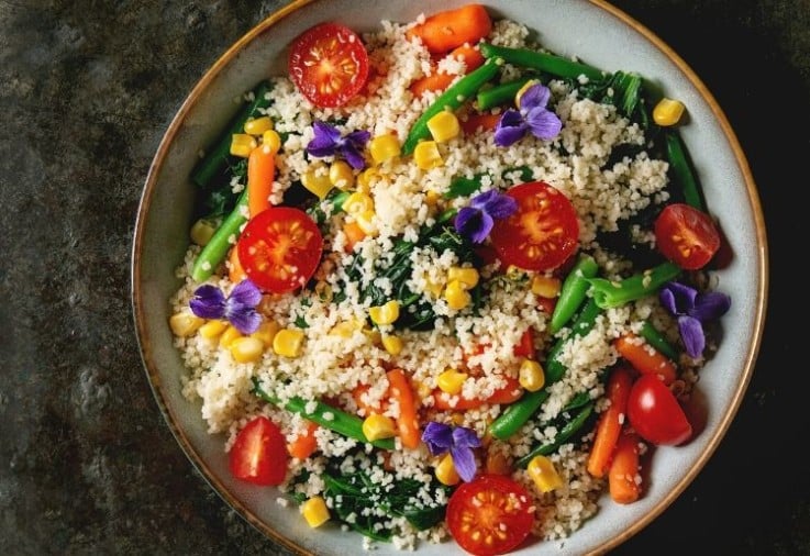 CousCous Salad served in a large earthenware bowl with lots of colourful vegetables