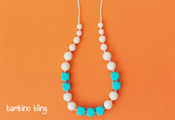 A blue and white teething necklace on an orange background