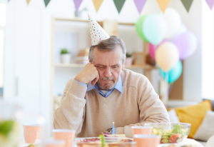 A man wearing a party hat sad and celebrating his birthday