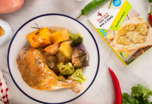 Roast chicken leg and thigh on a plate with roast vegetables and a packet of Nando's peri Peri bag and bake