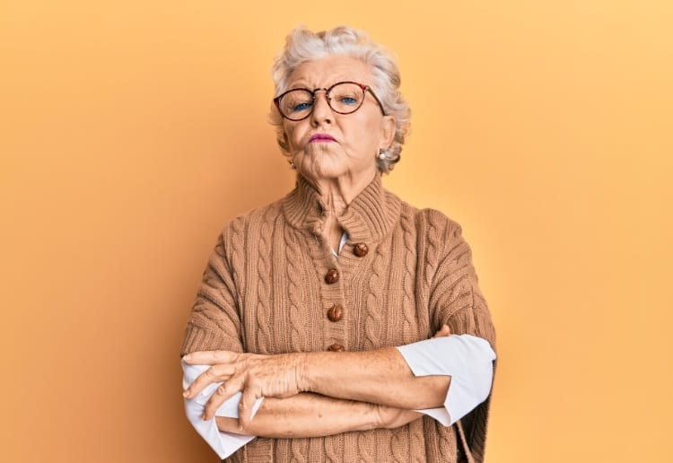 Senior grey-haired woman wearing casual clothes and glasses skeptic and nervous, disapproving expression on face with crossed arms. negative person.