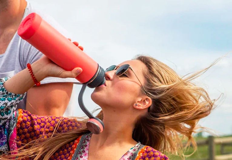 Woman drinking water from an insulated bottle.