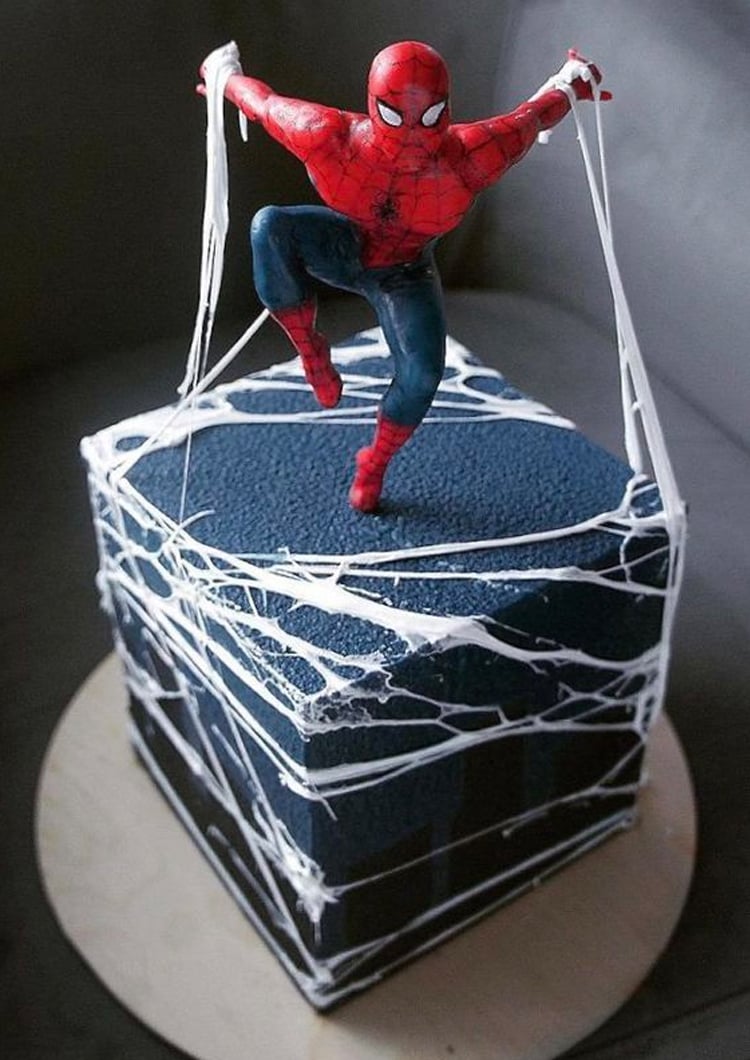 Cubed blue cake with Spiderman figure on top and white webs.