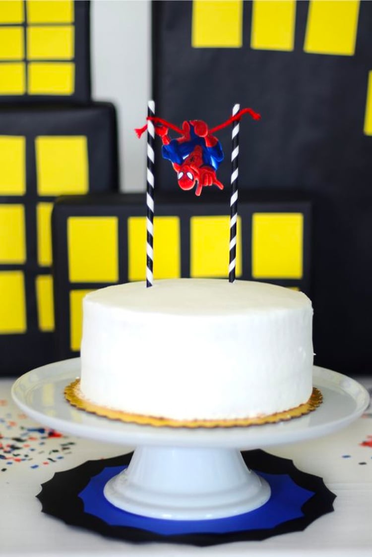 White cake with Spiderman figure on top.