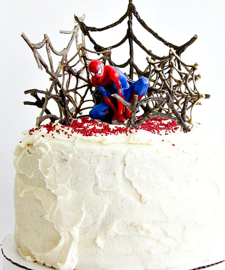 White frosted super hero birthday cake with superman figure on top.