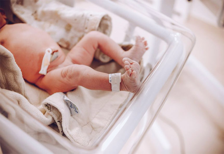 Newborn baby in a hospital bassinet.