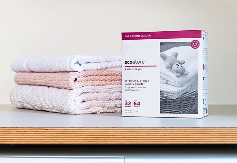 ecostore Baby Laundry Powder on a bench with folded towels.