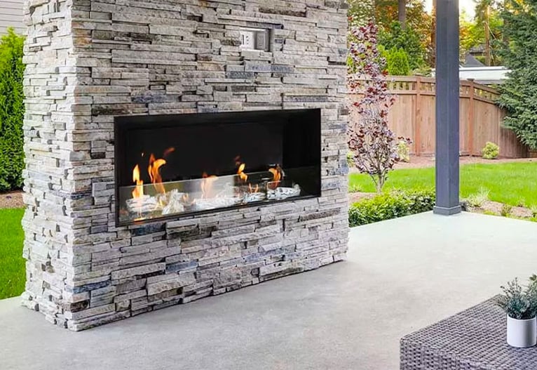 An outdoor gas fireplace built into a stone column.