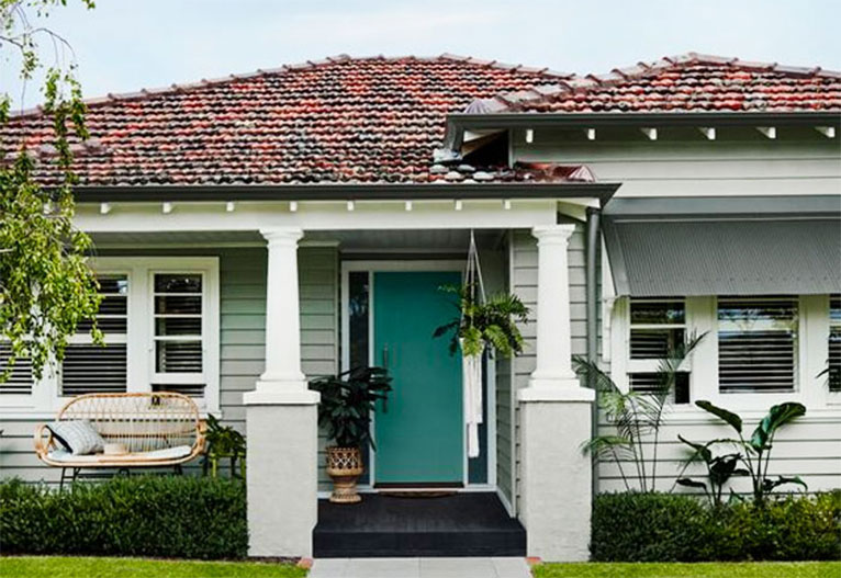 Front of a white weatherboard house with a muted green door.