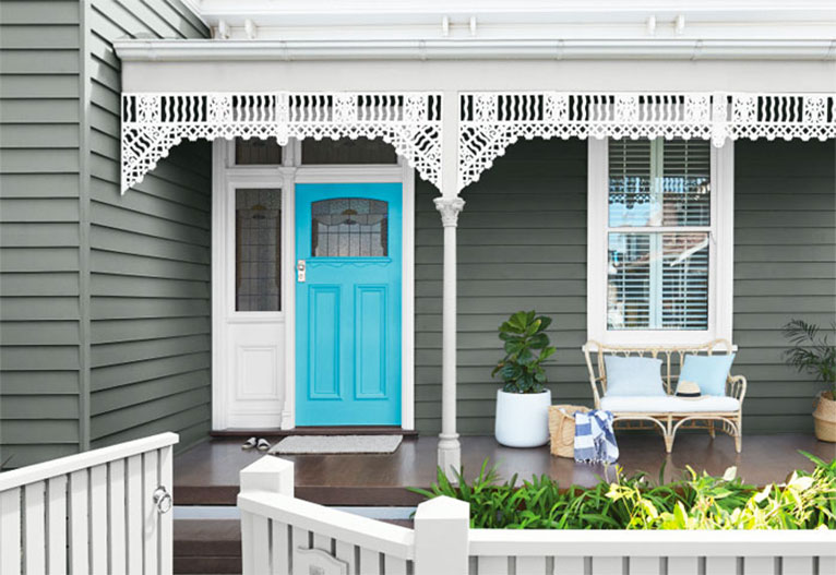 Front of a grey house with a bright blue door.