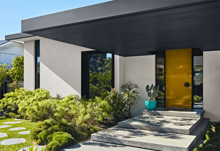 Front of a modern house with a bright yellow door.