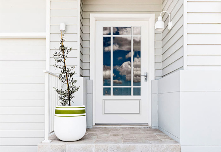 A white front door on a white weatherboard house.
