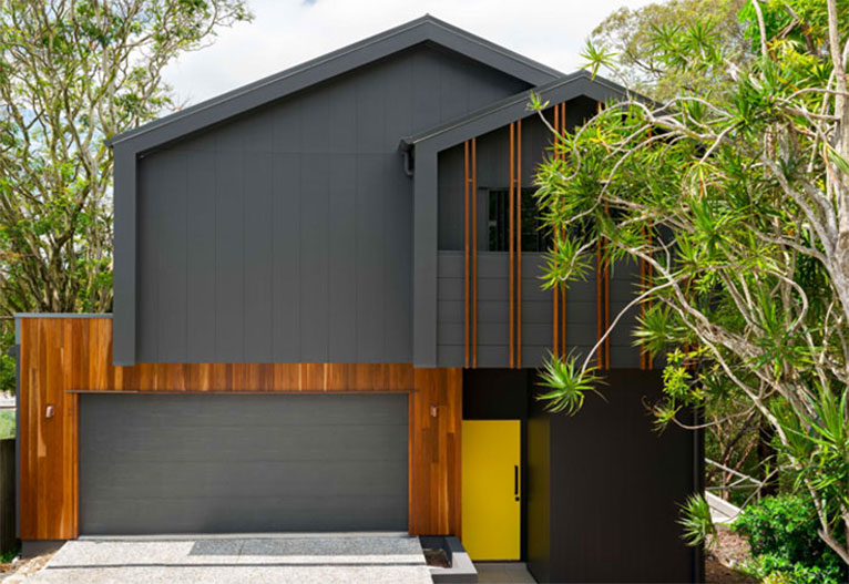 Front of a modern grey house with a yellow front door.