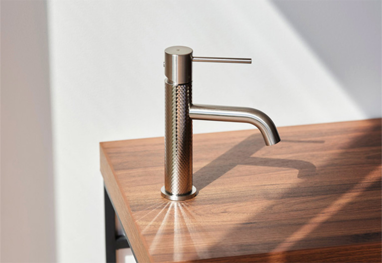 A brushed nickel tap mounted on a wooden bench.