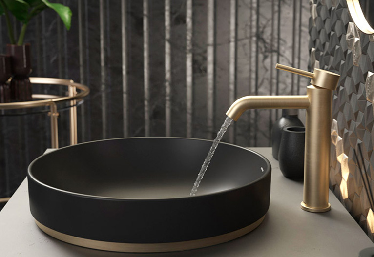 Water runs from a gold tap into a black basin.