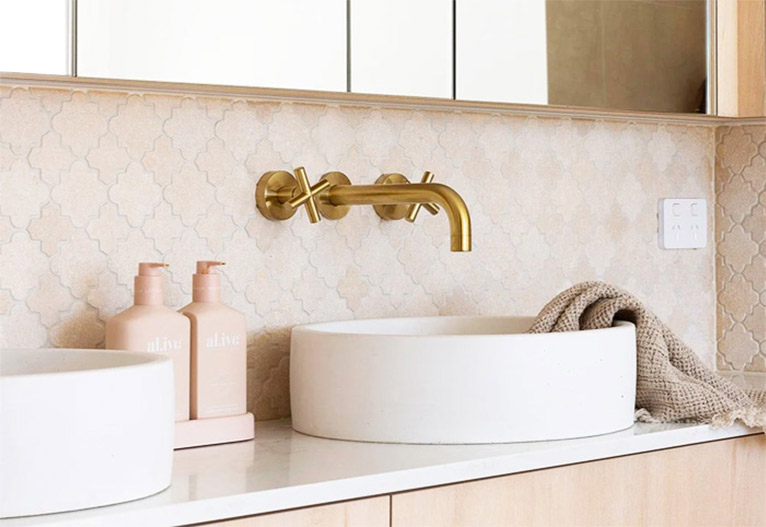 Brass wall-mounted taps above a white bathroom basin.