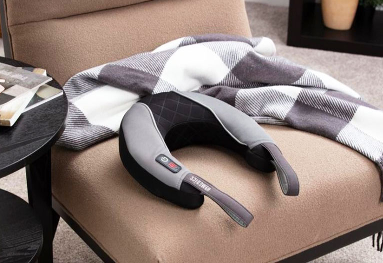 Neck massager sits on a lounge chair next to a scarf.