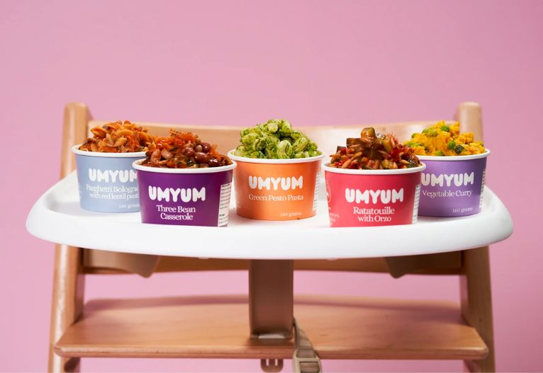 Assorted tubs of Umyum baby food on a high chair.