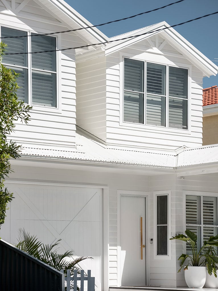 Top storey exterior of a white beach cottage in Sydney.