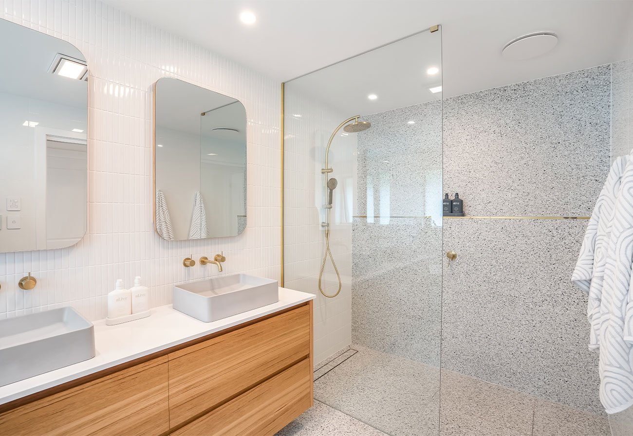 Modern bathroom with terrazzo shower and brass tapware.