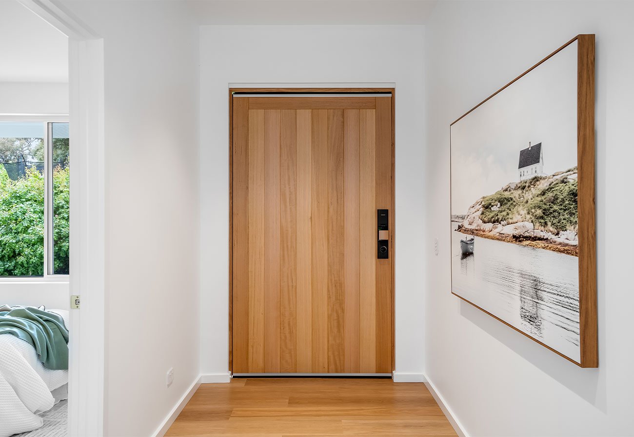 Timber front door shown from the foyer of a contemporary house.