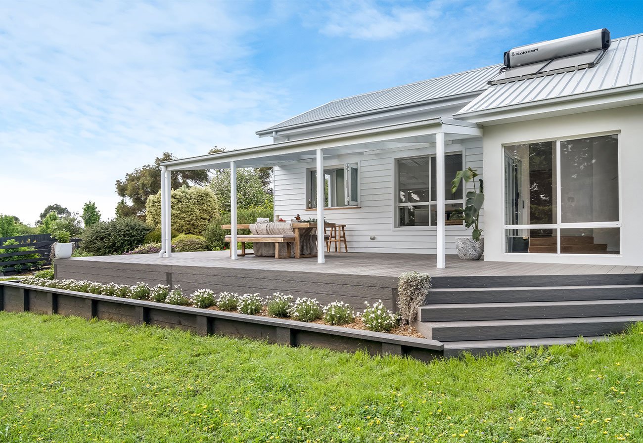 Exterior of white modern country home with grey decking.