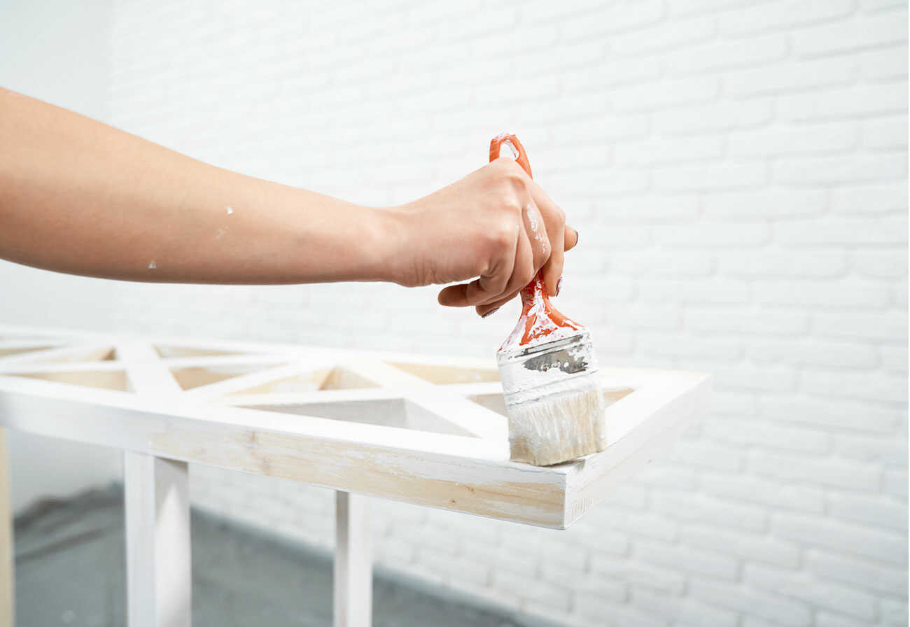 Person painting some old furniture with white paint.