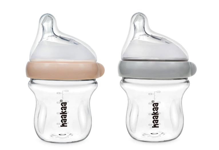 Haakaa glass baby bottles in peach and grey.