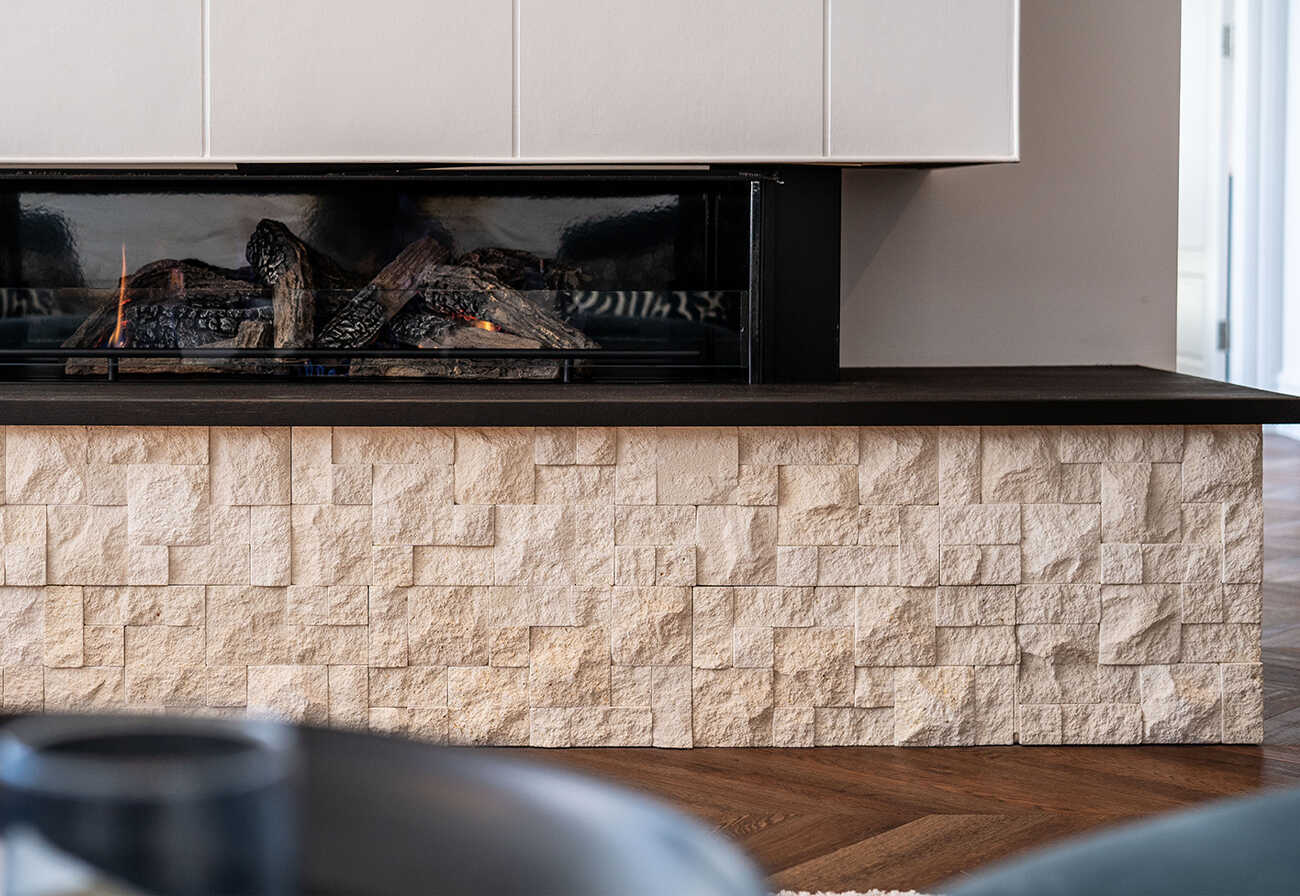 Limestone cladding below an indoor fireplace.