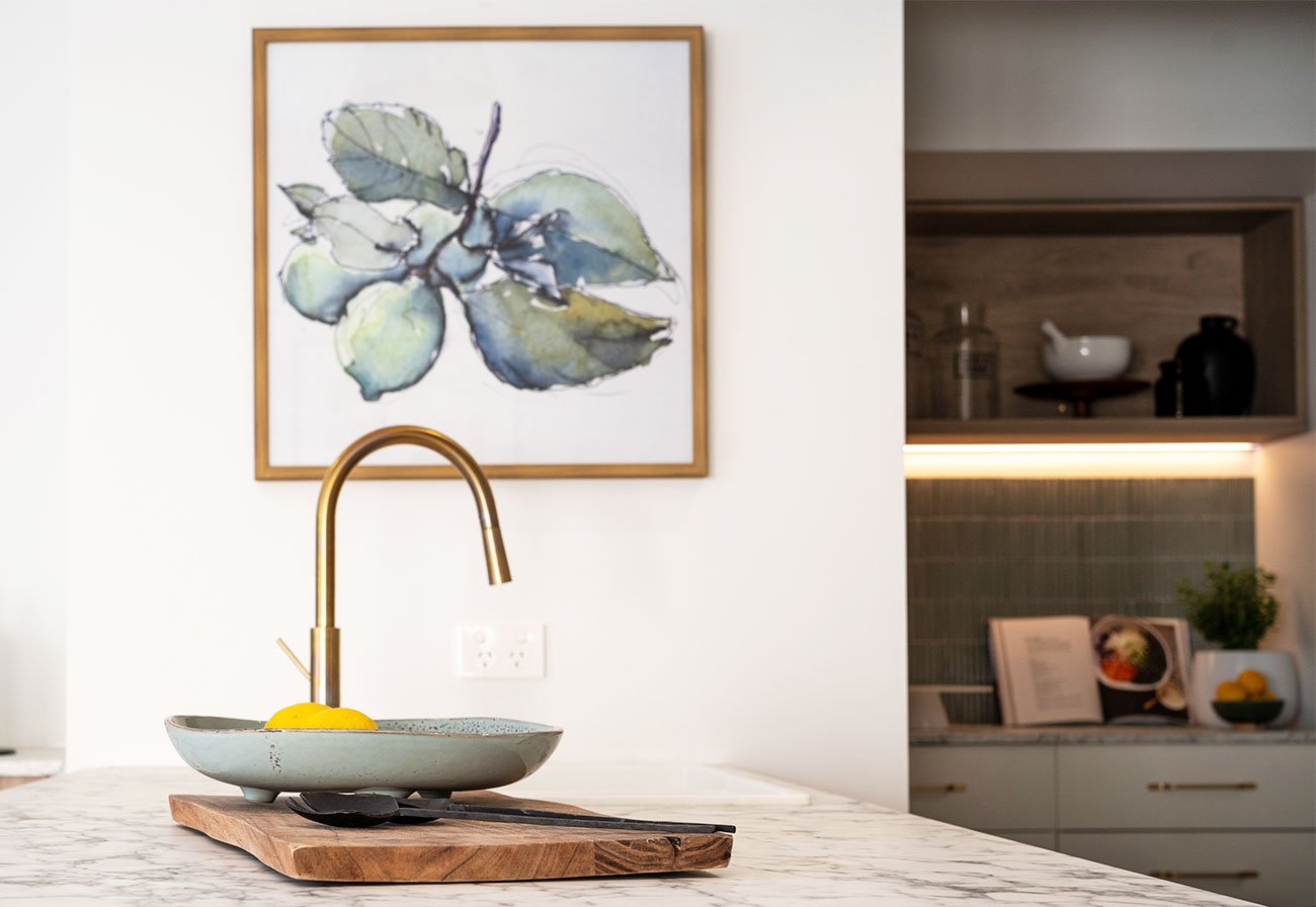 Brushed brass kitchen tap on a marble-look benchtop.