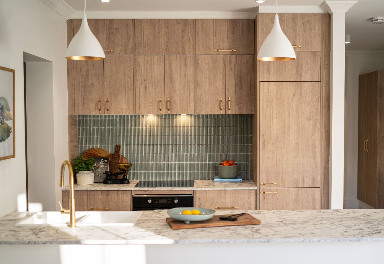 Studio apartment with maplenut cabinetry and sage green finger tiles.