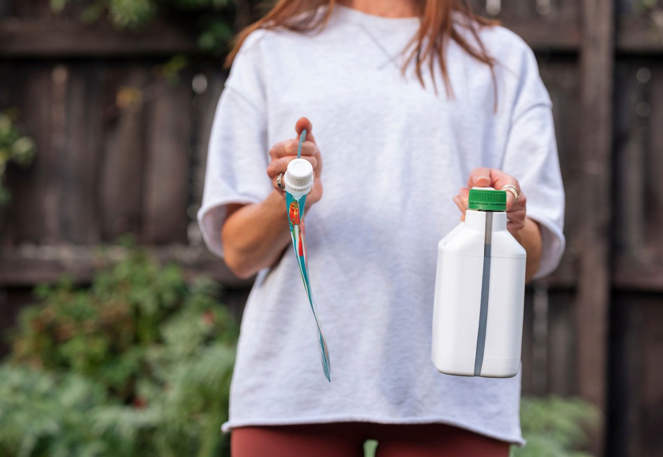 Woman holding two plant food containers.