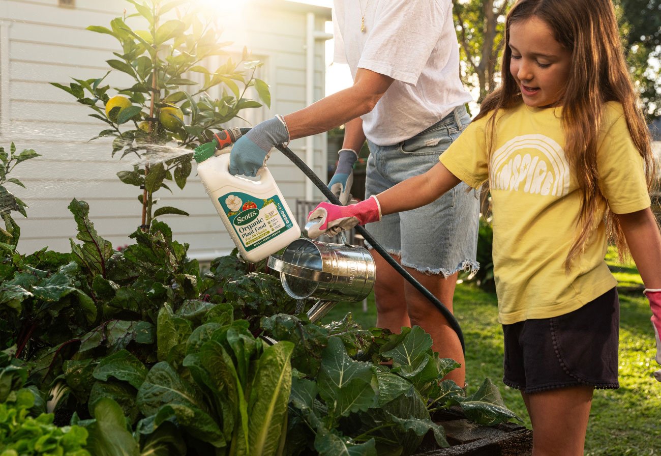 Woman and girl watering the garden.