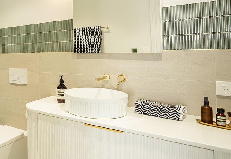 Brushed brass bathroom accessories on white vanity.