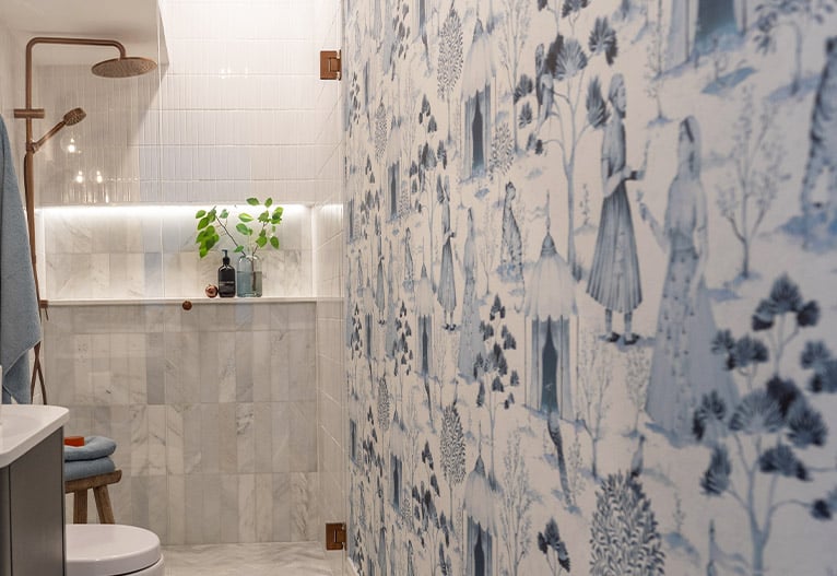 Guest bathroom with blue wallpaper and brushed copper taps.