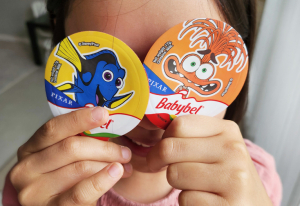 Child holding Babybel Mini Rolls over her eyes.